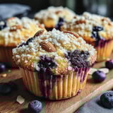 A close up of a blueberry muffin with nuts on top.