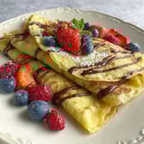 A crepe with chocolate and strawberries on top.